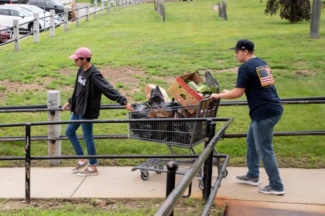 two volunteers wheel groceries to car at food pantry