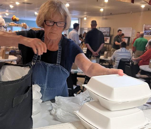 Volunteer serves hot meals to go
