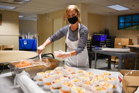 A volunteer serves fruit for the evening meal